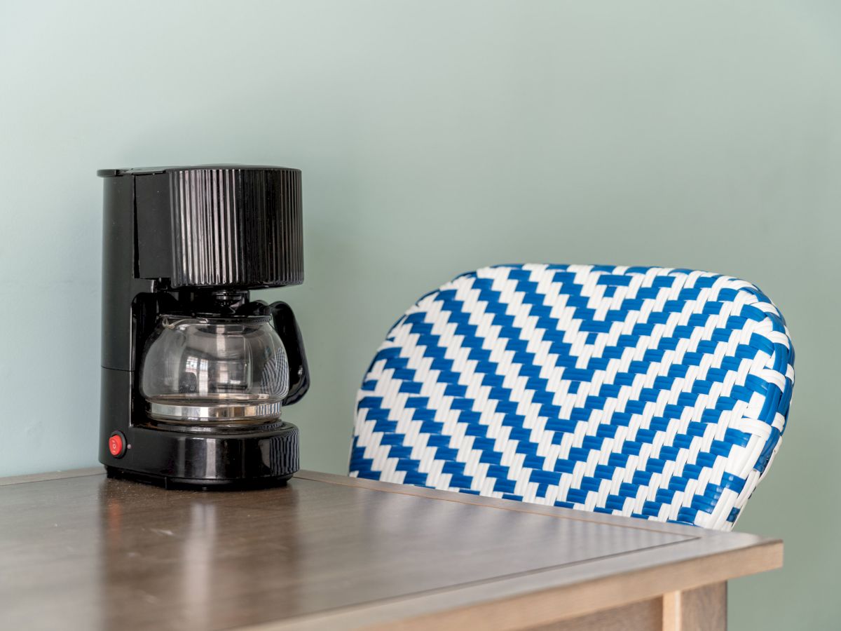 A black electric coffee grinder and a blue-white woven cable rest on a wooden table.