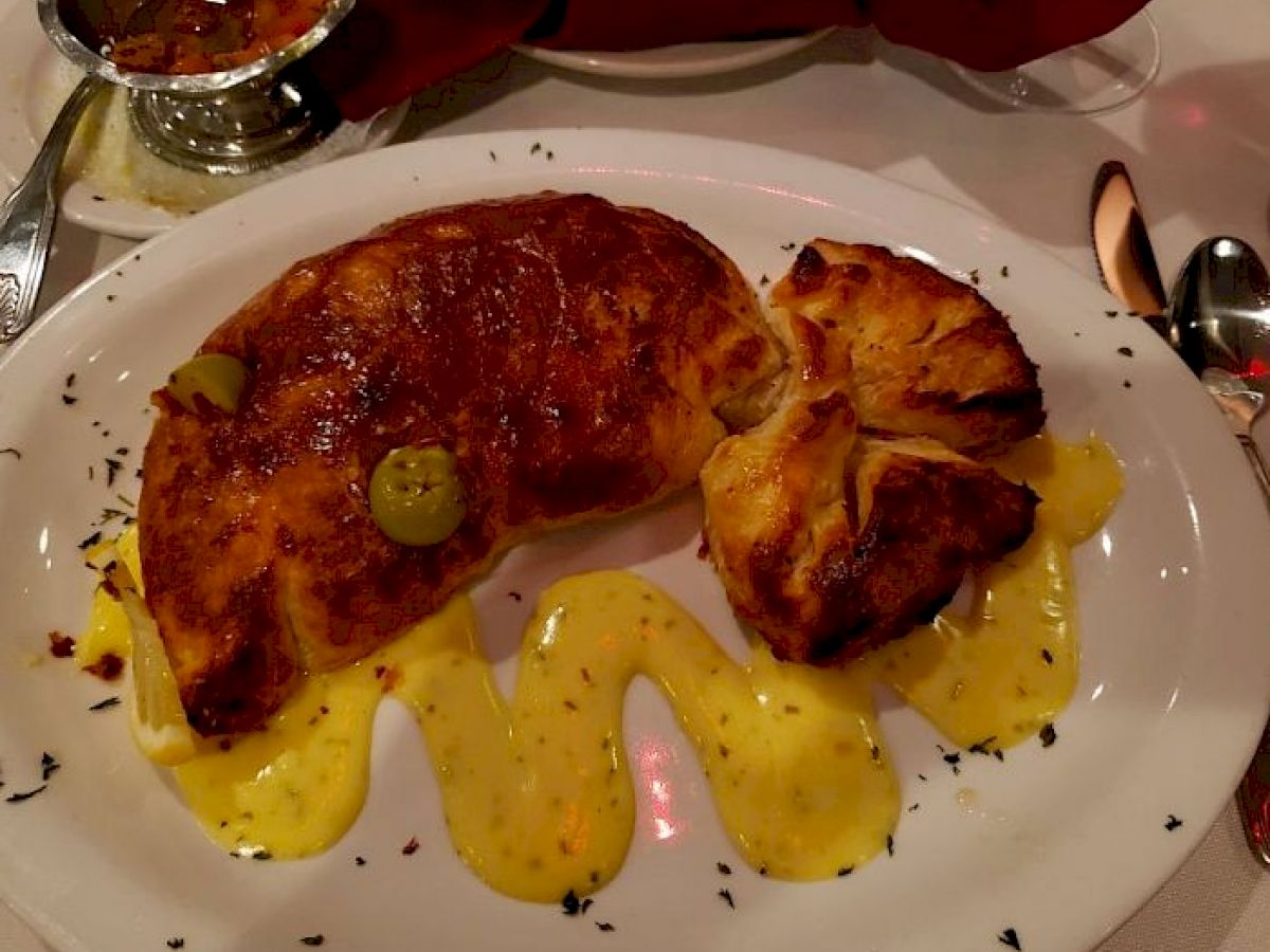 A croissant-like pastry with jalapeno slices and a dollop of sauce on an oval plate.